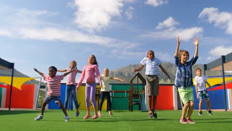 Front-view-of-mixed-race-schoolkids-exercising-in-the-school-playground-4k
