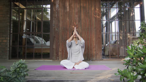 focused biracial woman practicing yoga on terrace, slow motion