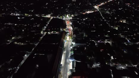 Nighttime-drone-flight-down-the-mainstreet-and-central-point-of-Wedi,-Klaten