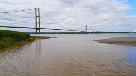 Marvel-at-Humber-Bridge-in-aerial-drone-footage,-12th-largest-single-span-globally,-gracefully-arching-over-River-Humber,-enabling-Lincolnshire-Humberside-transit-with-traffic