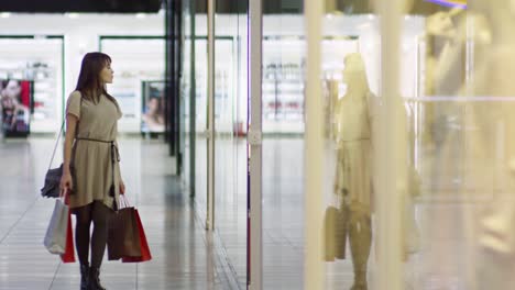 una mujer joven parando en la ventana de la tienda.