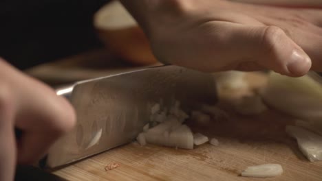 mincing onions using a sharp knife into a wooden board