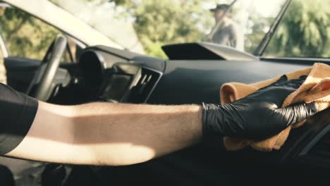 Close-up-of-a-male-wearing-black-gloves-cleaning-a-white-car-with-black-interior-with-a-microfiber-cloth-in-slow-motion