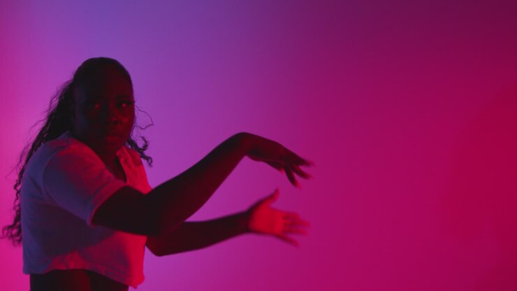 Studio Shot Of Young Woman Dancer Dancing Against Blue And Pink Lit Background 1