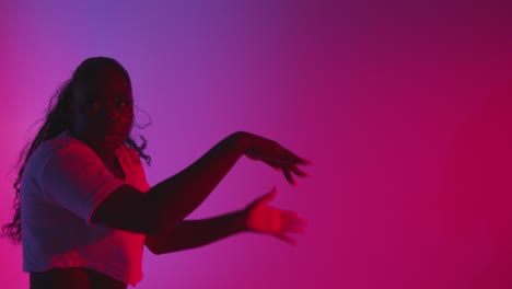 studio shot of young woman dancer dancing against blue and pink lit background 1