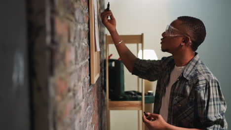 Young-African-American-man-checks-to-do-list-near-brick-wall