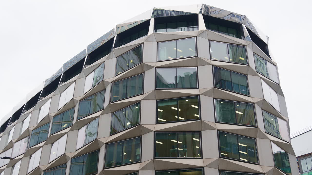 Close-up of a unique office building facade with angled, geometric window frames in London, England near the financial center