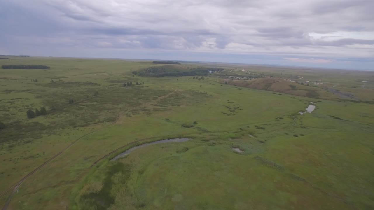 воздушный вид зеленого поля и небольшой деревни под облачным небом