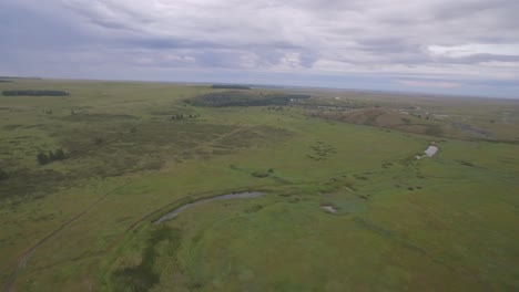 vista aérea de un campo verde y un pequeño pueblo bajo un cielo nublado