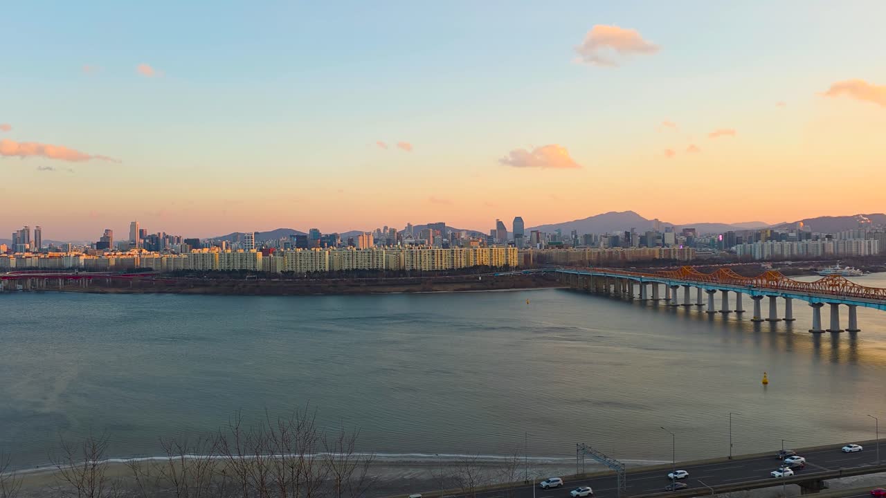 Panoramica aerea in tempo reale che rivela lo skyline dorato di Seul al tramonto lungo il fiume Han, dal ponte Seongsu al ponte Donho, con il traffico dell'autostrada Gangbyeonbuk-ro.