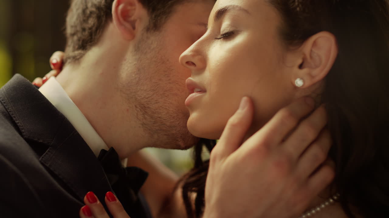 hombre guapo besando la mejilla de la mujer al aire libre. pareja sensual posando en el parque