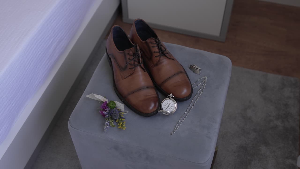 Brown leather shoes with wedding accessories on a soft velvet ottoman