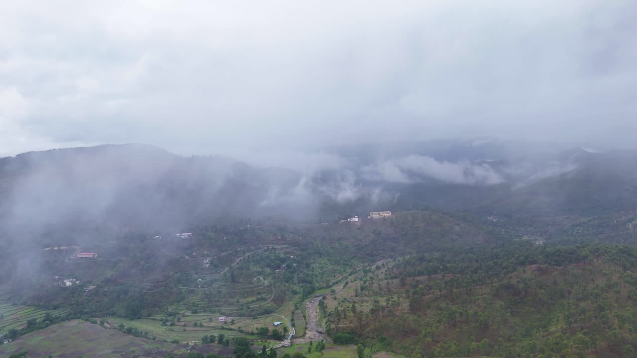 Aerial drone shot showcasing mist rolling over mountain ridges at sunrise.