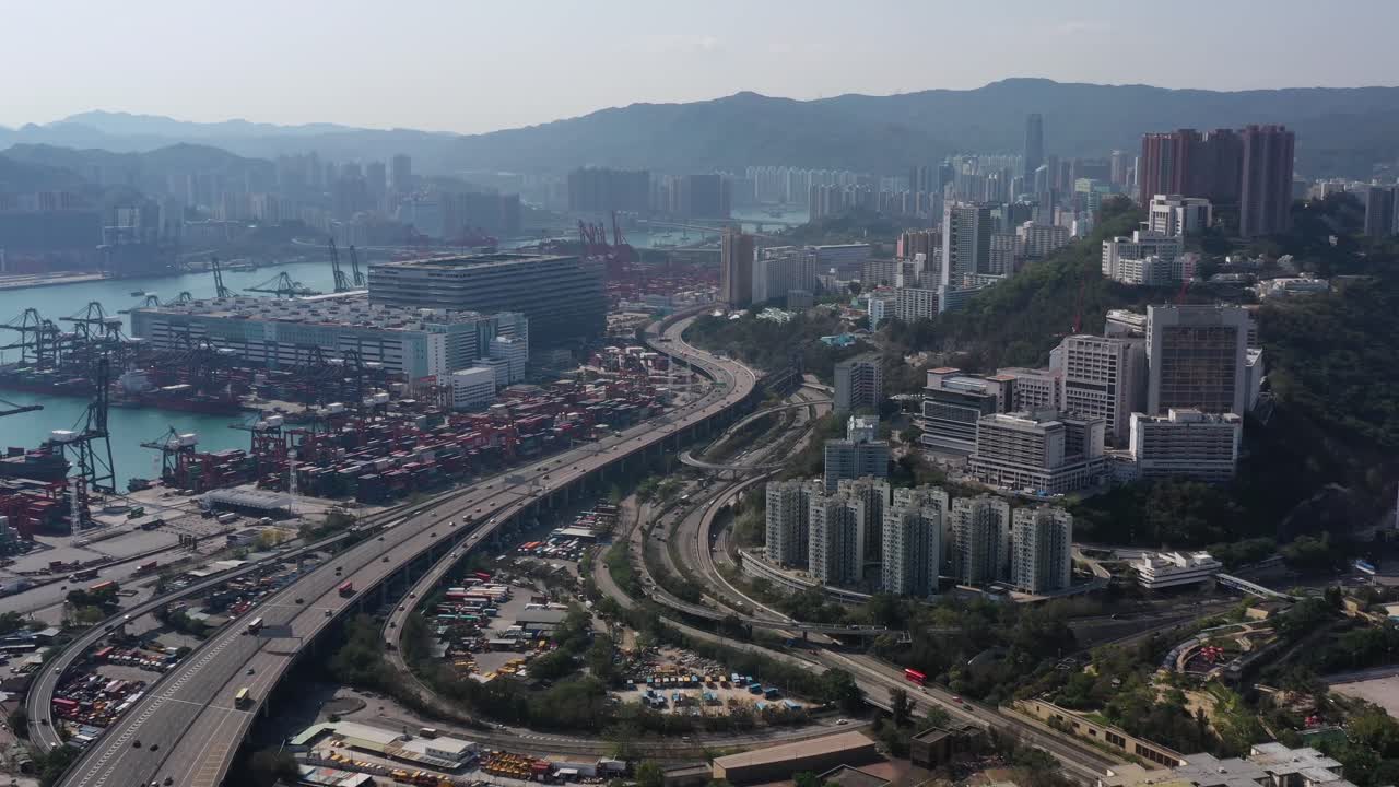 Aerial View Of Hong Kong High-Rise Buildings in Lai Chi Kok. Light Traffic On Highway. Tall residential buildings stay against large industrial facility, international cargo port of Hong Kong