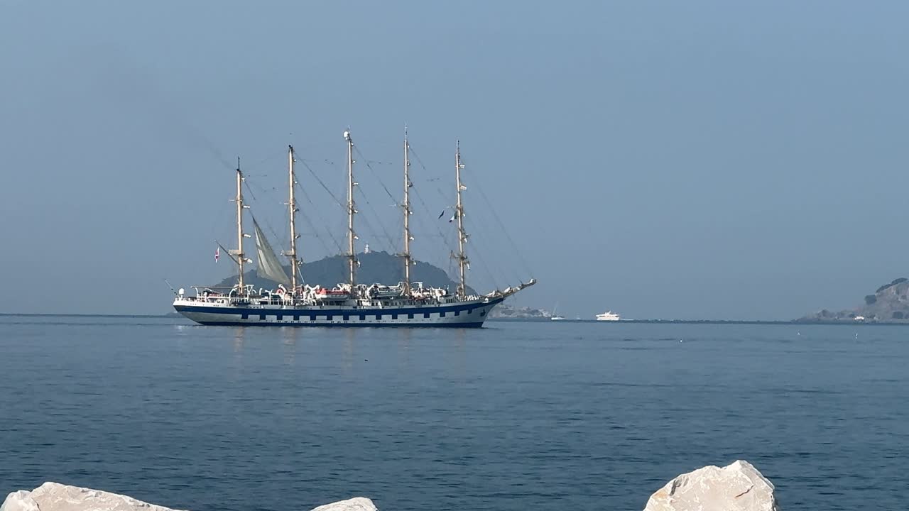 Tall ship slowly moving in calm water.