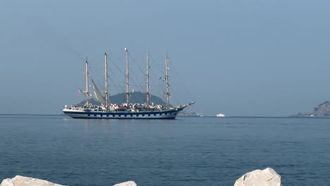 tall ship slowly moving in calm water.