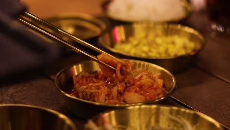 chopsticks serving kimchi into a bowl