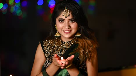 beautiful young woman lighting diya - oil lamp in traditional clothing on the occasion of diwali.