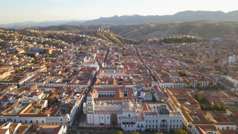 Vista-Aérea-Sobrevolando-La-Pintoresca-Ciudad-Colonial-De-Sucre,-Bolivia-Al-Atardecer