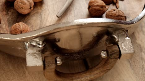 nueces y cascanueces en un plato redondo de plata. vista desde arriba. cascanuecas y nueces. nueces en fondo de madera. herramienta para nueces. frutos secos deliciosos y saludables.