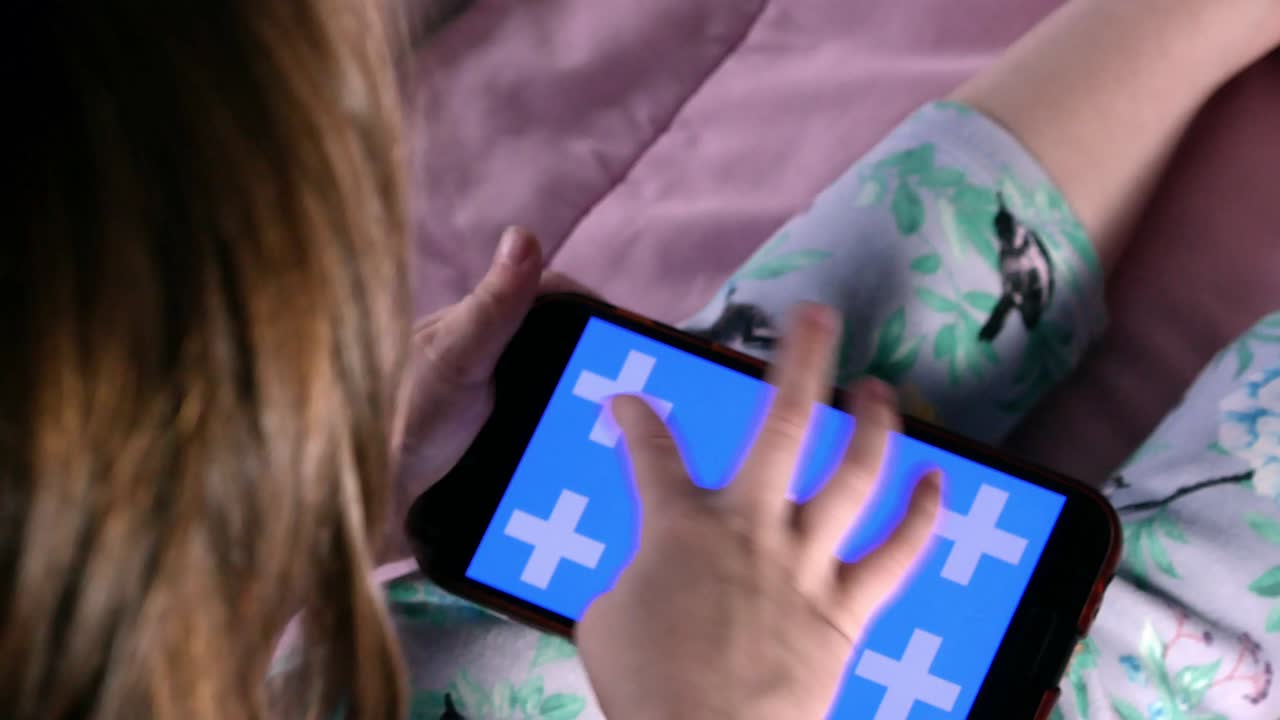 un teléfono inteligente en manos de un niño, la pantalla está retroiluminada con una indicación de color azul.