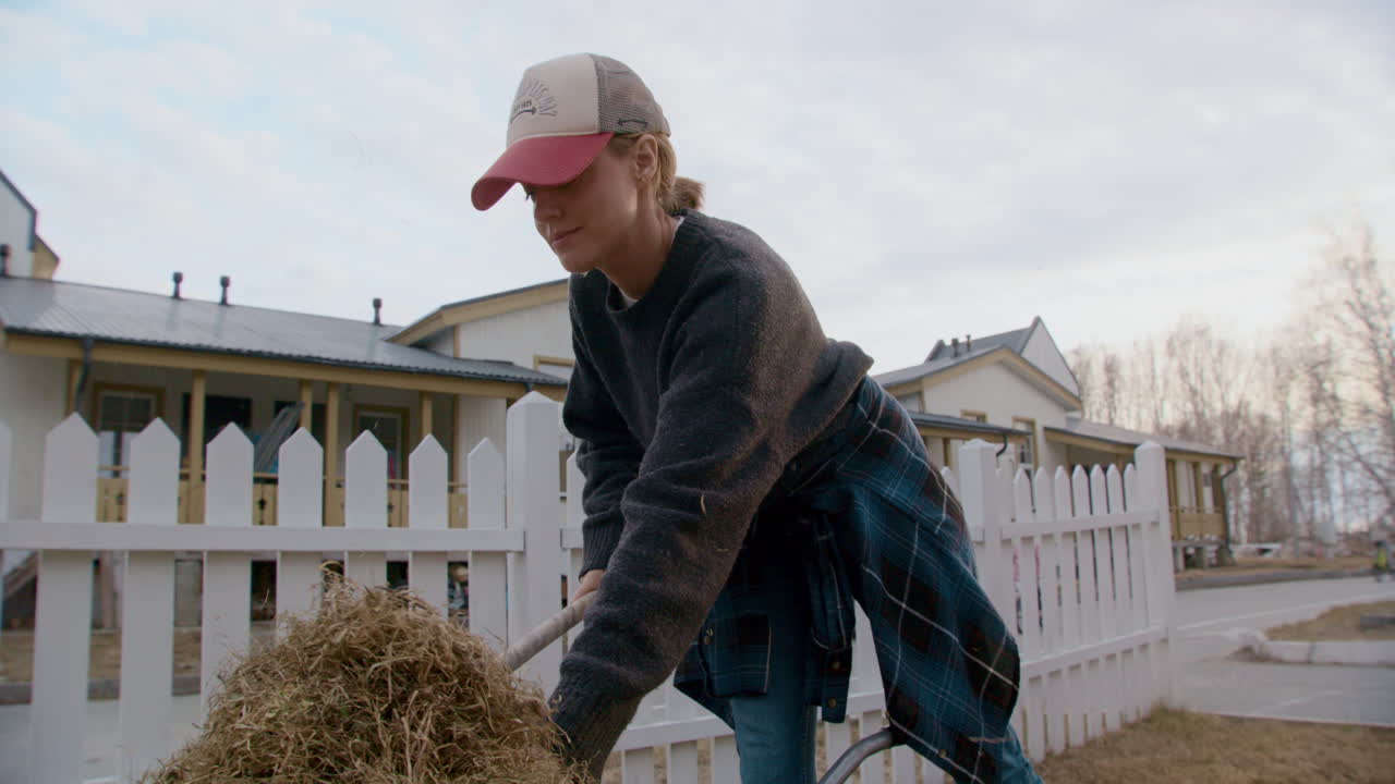 Woman raking hay in a yard