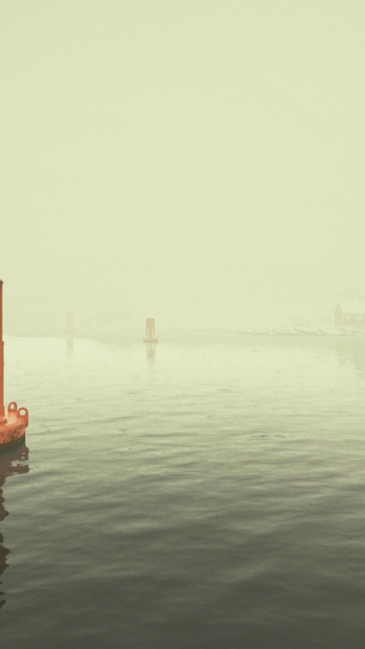 Matin brumeux avec une bouée orange naviguant dans des eaux calmes dans un port