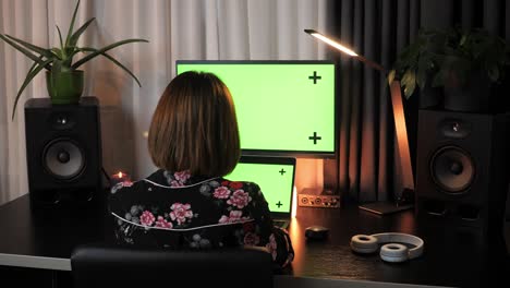 business concept. woman working late, sitting office desk, using laptop computer with mock-up green screen. female at home office desk working online with pc software apps. technology concept