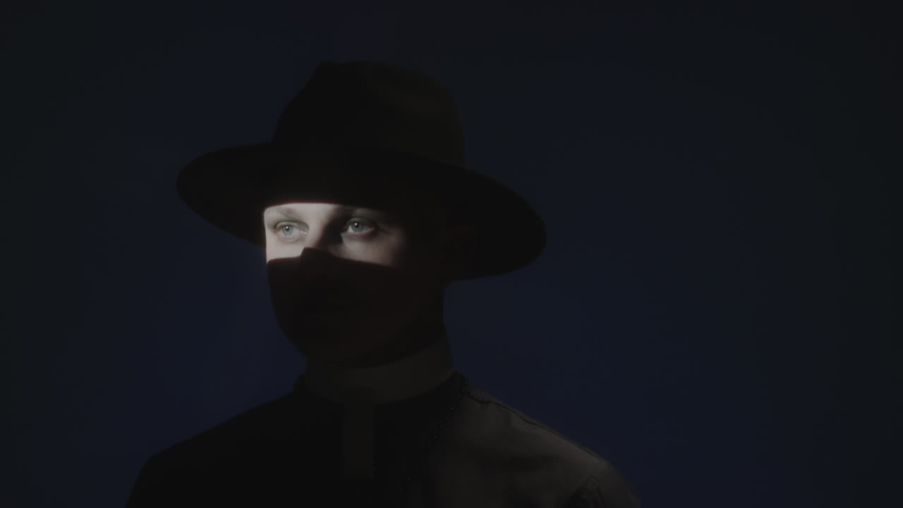 Priest with Shadow on Face Posing in Dark Studio