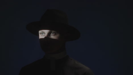 priest with shadow on face posing in dark studio
