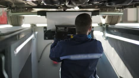 mechanic inspecting car undercarriage in service pit