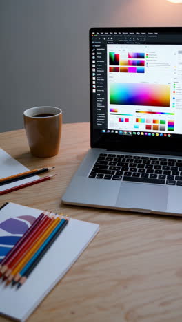 laptop with design software, art supplies and coffee