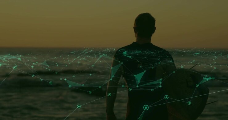 Muž stojí s deskou čelem k moři, zatímco letí racek, což způsobuje, že se tyrkysová technologická síť vlní na trupu.