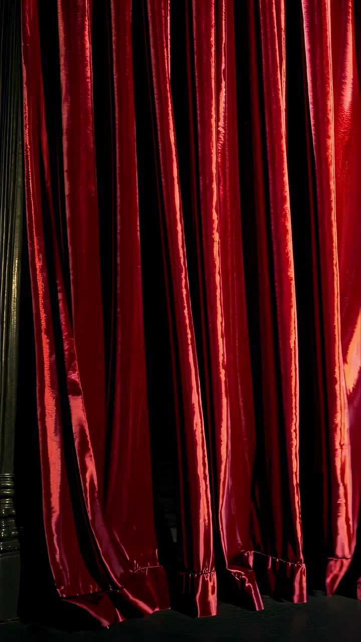 Un video ravvicinato drammatico di tende di velluto rosso parzialmente aperte, che rivelano l'oscurità dietro.
