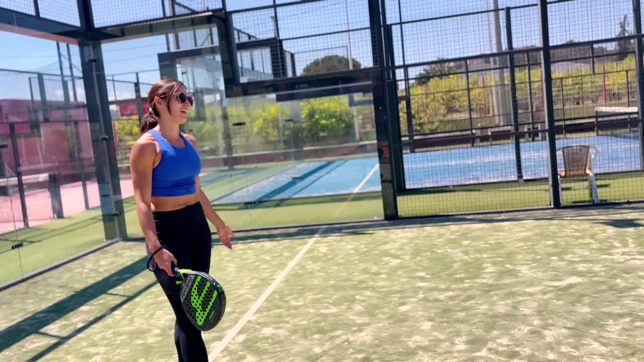Young sportswoman and man couple playing padel tennis in slow motion. Hitting padel ball in slow mo at padel court.