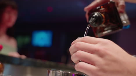 4k slow motion bartender close up pouring alcohol shot into shot glass at busy bar