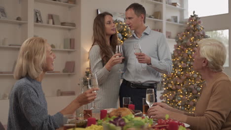 adultos jóvenes y sus padres ancianos brindando y celebrando la cena de navidad en casa