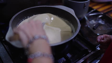 close-up view of hands while cooking from the basic argentinian bagna cauda ingredients in a cooking pot on the stove.
