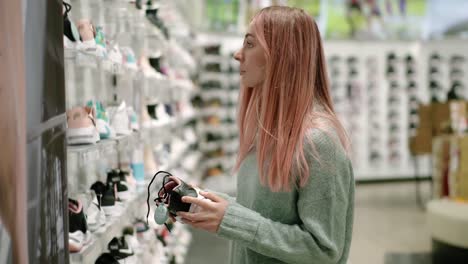 shopping in sport shoes store, woman is choosing sneakers