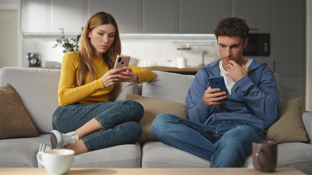 Internet addicted couple ignoring each other sitting couch at home living room