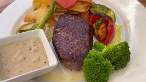 juicy sirloin fillet steak with peppercorn sauce, vegetables and potatoes at a restaurant, delicious high quality beef, 4k shot