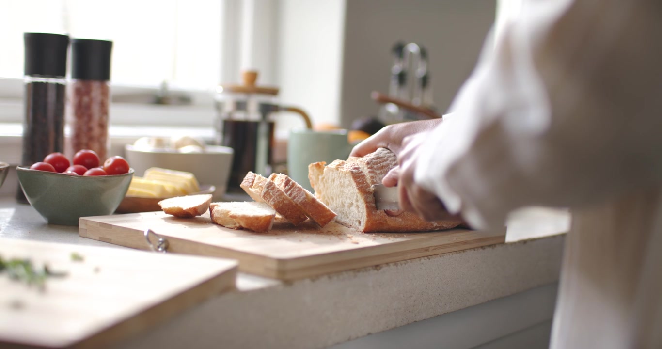 African American woman slicing loaf with knife, arranging slices on cutting board, making breakfast