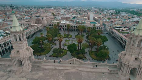 Bei-Bewölktem-Tag-Schwenkt-Die-Drohne-Von-Links-Nach-Rechts,-Fängt-Die-Rückansicht-Der-Arequipa-Kathedrale,-Ihrer-Zwillingstürme-Und-Der-Plaza-De-Armas-Ein-Und-Endet-Mit-Einer-Frontalansicht