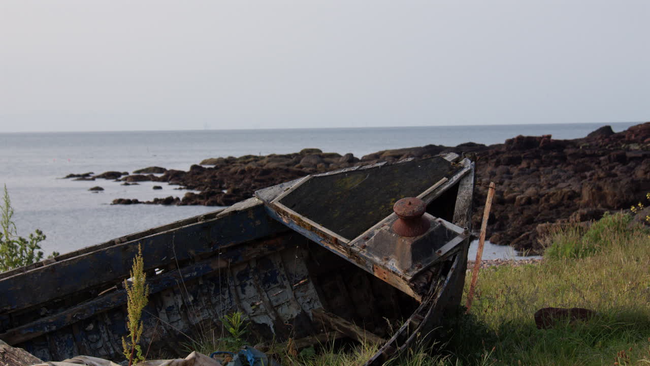 Mid shot of an abandoned derelict broken boat at the old harbour at low tide at Auchmithie