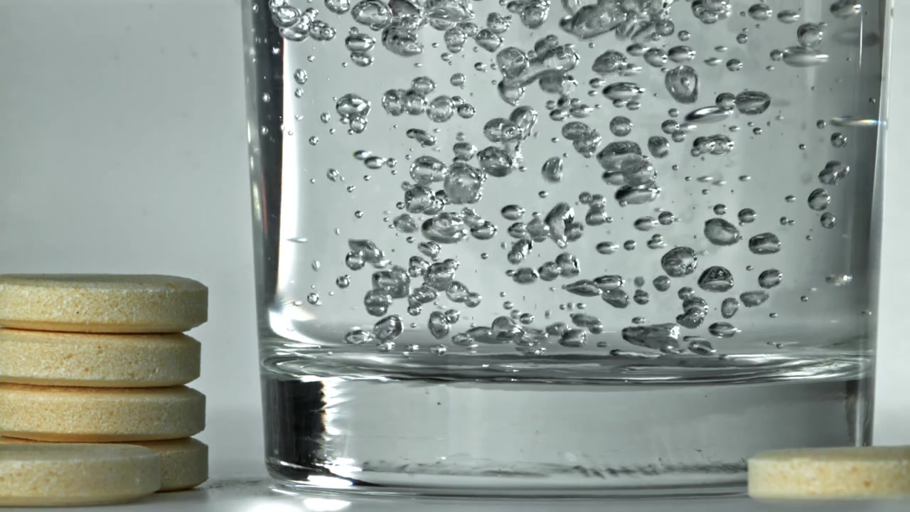 Comprimé effervescent se dissolvant dans de l'eau claire avec des bulles montantes