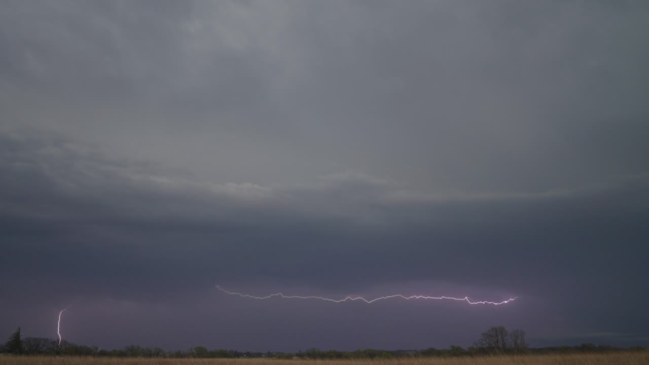 Lightning Flickers Beneath a Looming Storm, Casting an Eerie Glow Over the Darkening Horizon - Static Shot