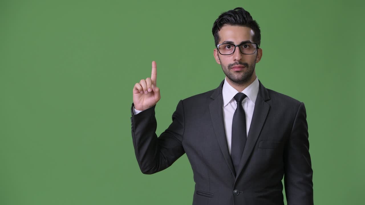 joven empresario persa barbudo y guapo contra un fondo verde