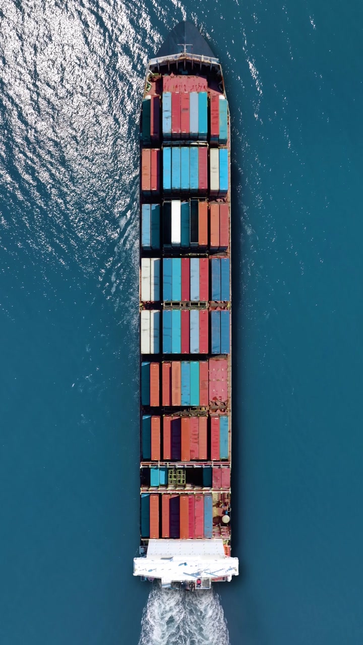Container ship sailing through clear waters, transporting valuable cargo. vertical video