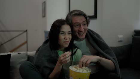 smiling couple eat popcorn and watch a movie together