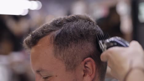 barber haircut hair using electric trimmer, barber makes haircut for groom customer at barber shop